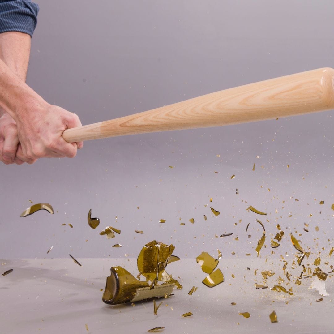 person using a bat to smash glass
