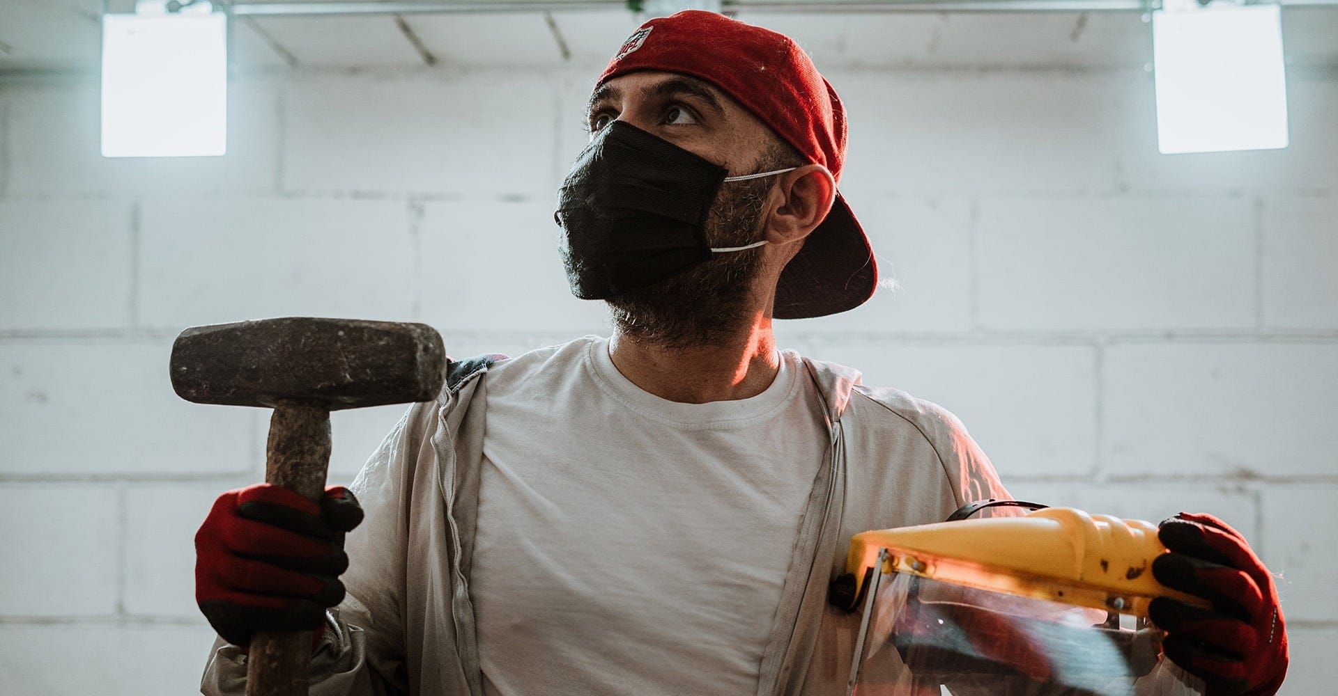 A man holding a hammer and face shield in a rage room