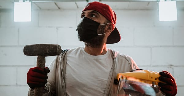 A man holding a hammer and face shield in a rage room